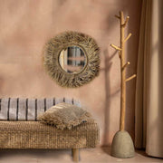 Handgeflochtener runder Naturgras-Spiegel Tahiti an einer hellen Wand im Flur Boho Interior Design.
