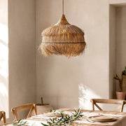 Rattan Pendelleuchte Liana über einem gedeckten Tisch für zwei Personen, warmes Licht scheint durch das natürliche Rattan und schafft eine gemütliche Boho Atmosphäre im Restaurant. 106482-216746 Illuzia