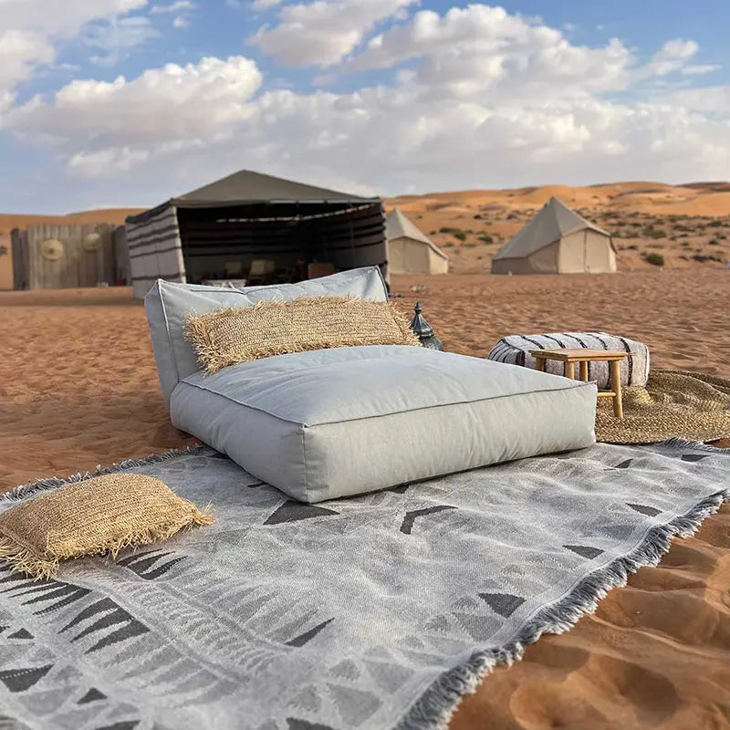 Boho Lounge Kissen und Sitzfläche im Wüsten-Glamping mit Zelten im Hintergrund, inspiriert von außergewöhlichem Hotel-Ambiente
