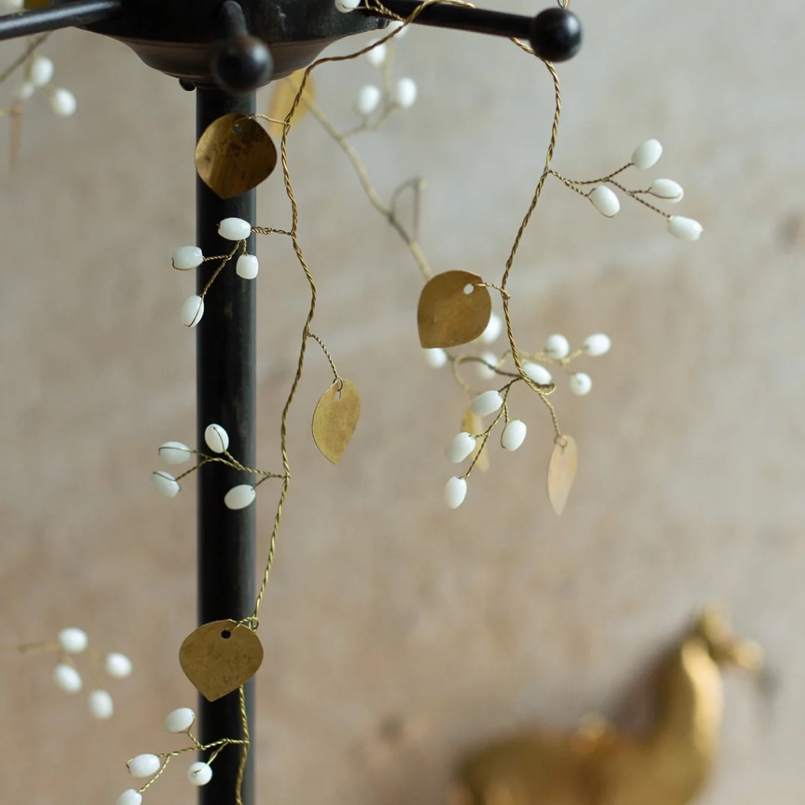 detail der deko: goldene deko girlande aus metall mit weißen beeren von der marke weldaad an einer garderobe dekoriert