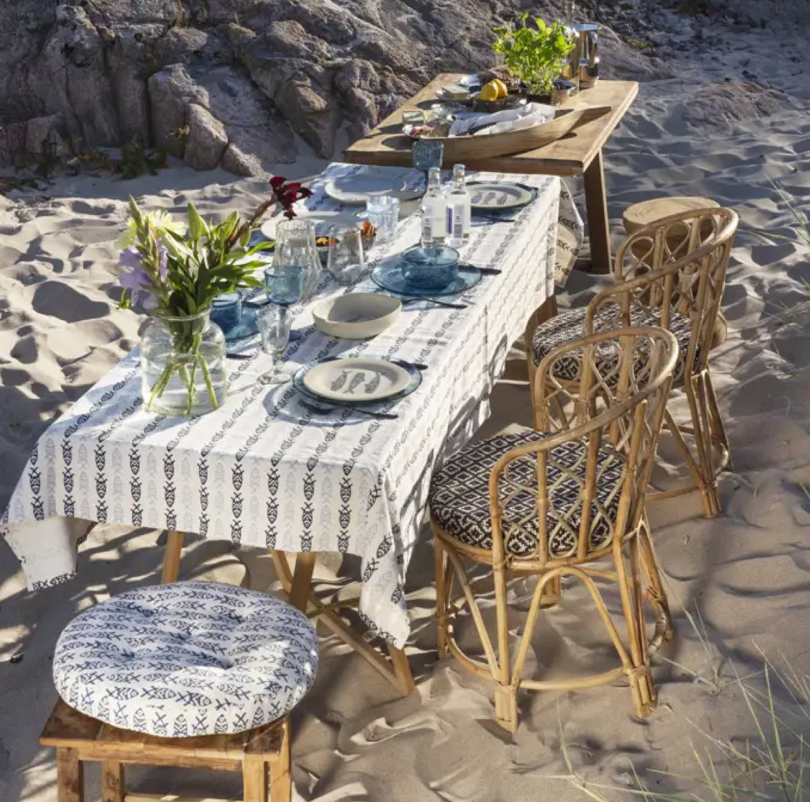 Festlich gedeckte Tafel im Strand mit mehreren MADAME Bambusstühlen für ein sommerliches, cosmopolitisches Outdoor-Event.