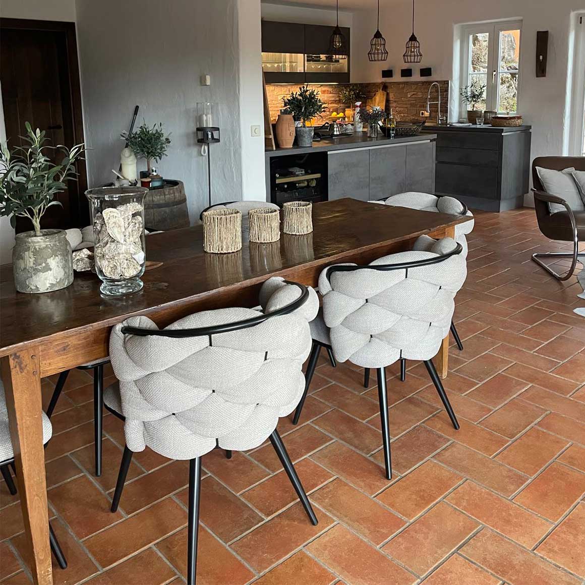 Sechs beige Esszimmerstühle im modernen Landhaus Still an einem großen Esstisch in einem gemütlichen Esszimmer mit Küche