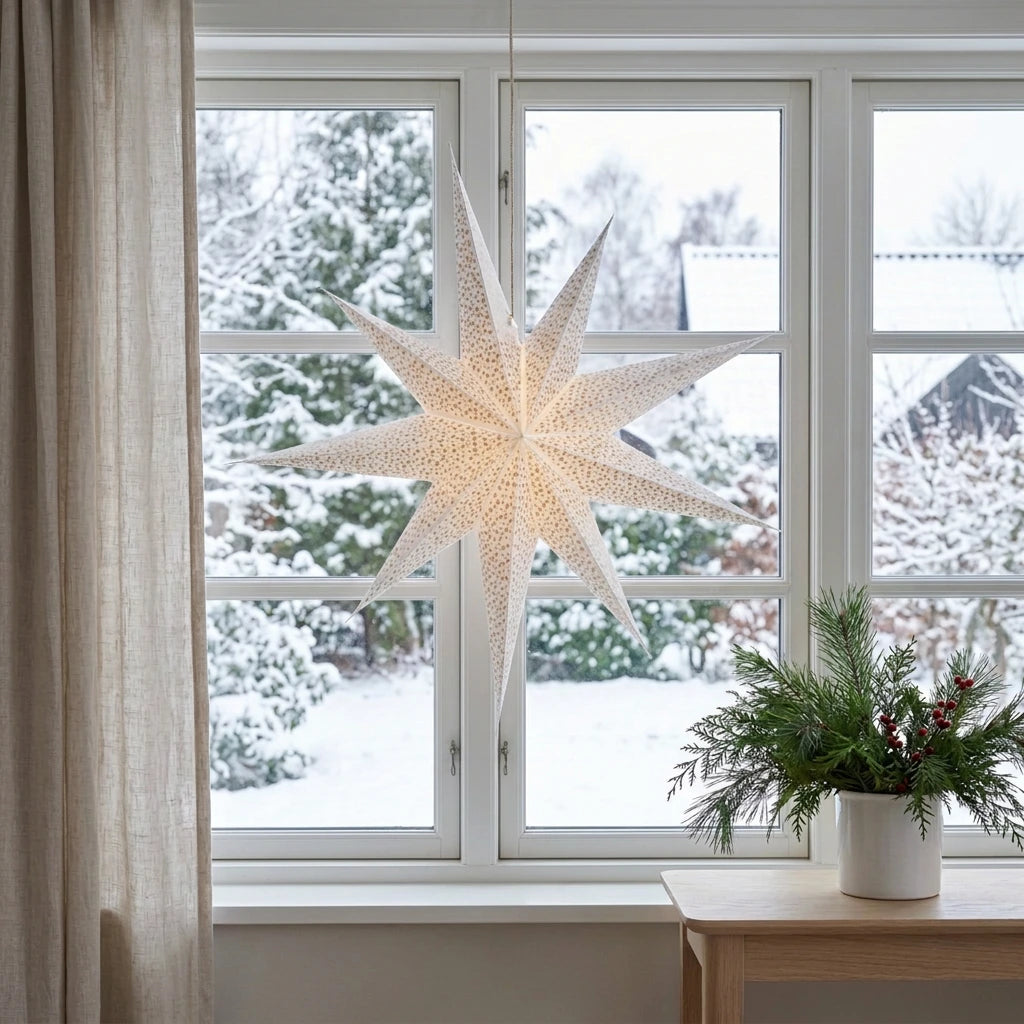 Weißer Papierstern mit Gold Glitzer als Weihnachtsbeleuchtung im Fenster innen