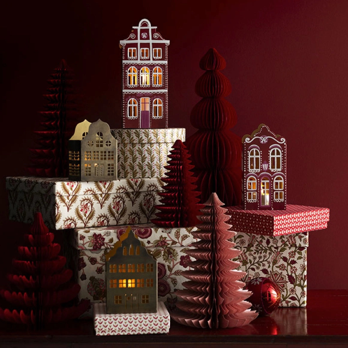 Rotes Lebkuchenhaus Scarlet aus Metall mit handbemalter Fassade und warmem goldenen Innenlicht dekoriert in einer weihnachtlichen Szene