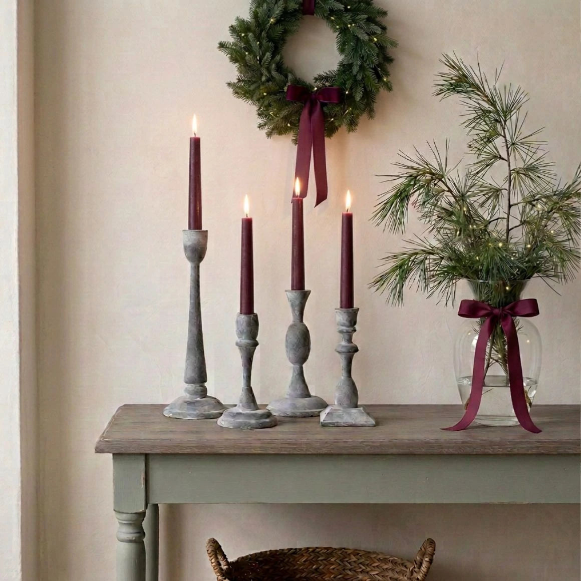 Vier graue Rosie-Kerzenständer aus Eisen von Affari of Sweden mit bordeauxroten Stabkerzen, dekoriert mit winterlichen Kiefernzweigen im skandinavischen Landhausstil.