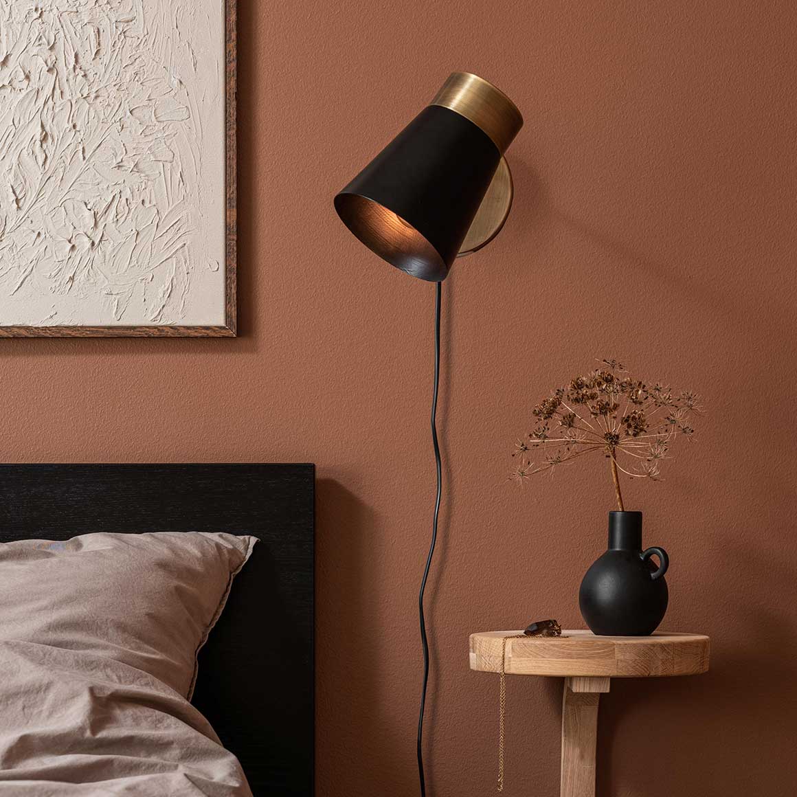 Schwenkbare schwarze Wandleuchte als Leselampe neben dem Bett im Hotel Schlafzimmer mit warmem Licht