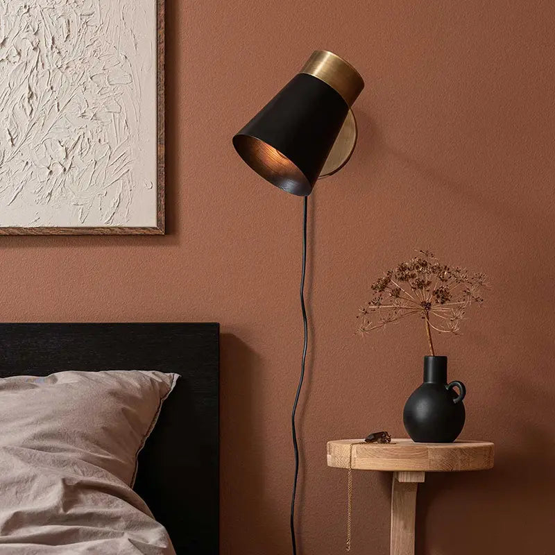Schwenkbare schwarze Wandleuchte als Leselampe neben dem Bett im Hotel Schlafzimmer mit warmem Licht