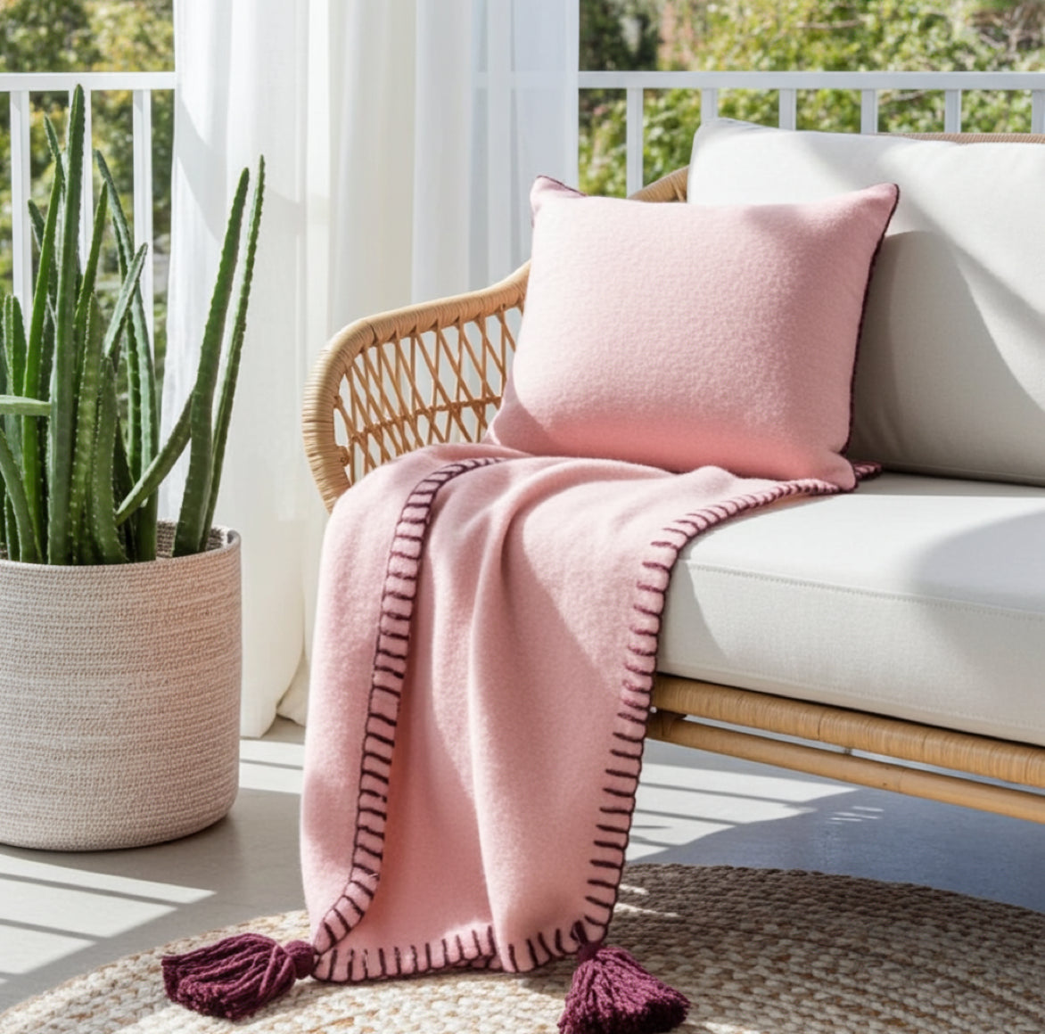 Gemütliche Kuscheldecke in Altrosa drapiert auf einem hellen Sofa im modernen Wohnzimmer