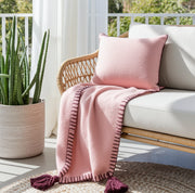 Gemütliche Kuscheldecke in Altrosa drapiert auf einem hellen Sofa im modernen Wohnzimmer