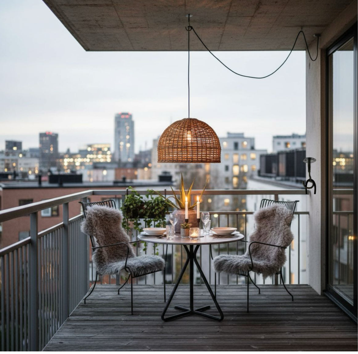hängende Deckenlampe als Lampe über Esstisch auf einem Balkon in der Stadt die gemütliches Licht verbreitet durch Naturmaterial geflochtenen runden Lampenschirm