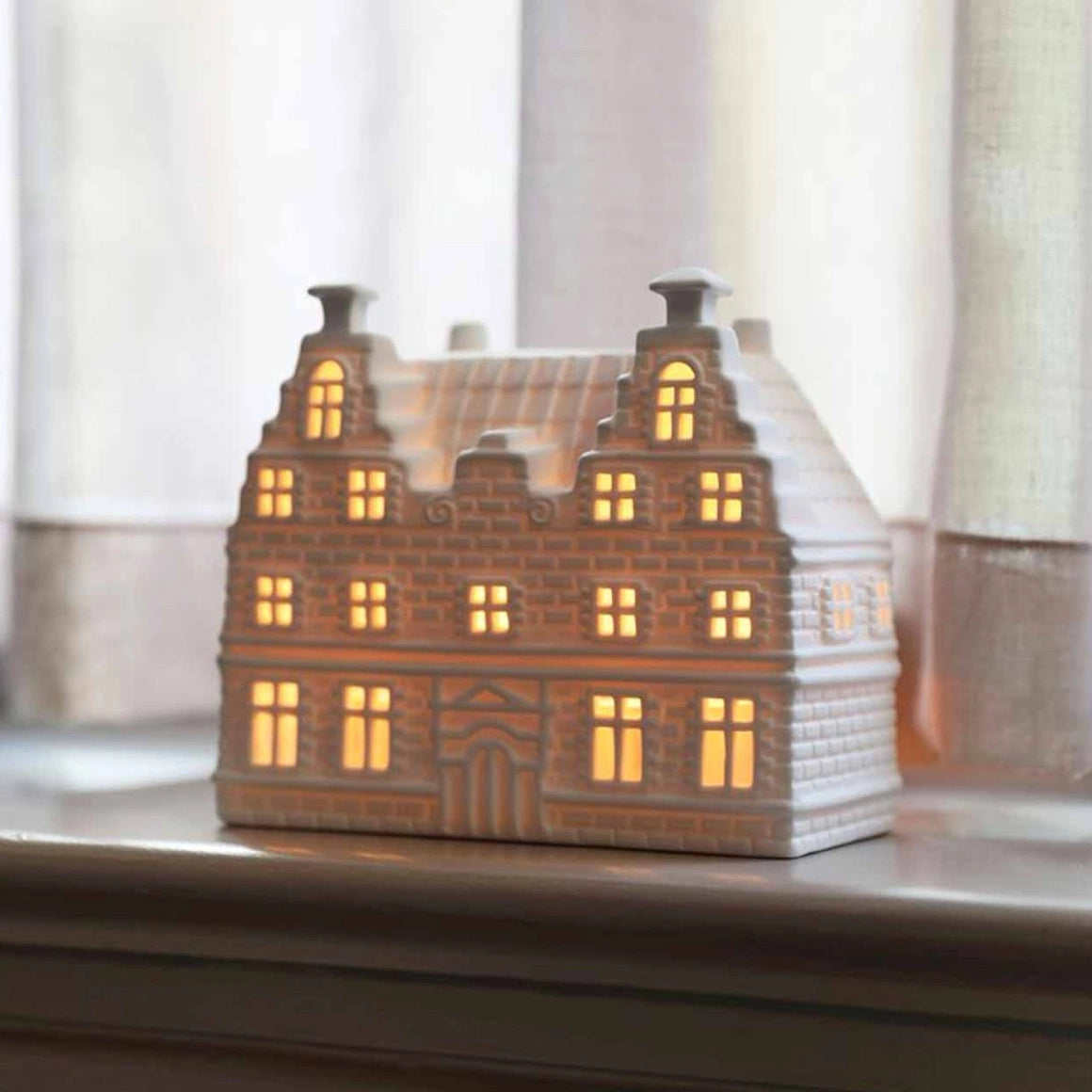Großes Lichthaus Schule mit mehreren Giebeln und Kamin leuchtend mit Licht im Fenster vor Vorhang dekoriert