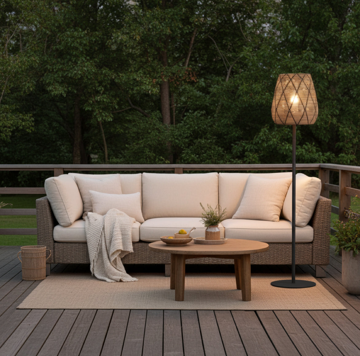 Gemütliche Stehlampe im Landhaus Stil neben einem bequemen Sofa mit Polstern und einem Outdoor Teppich auf einer Terrasse mit Holzbodem