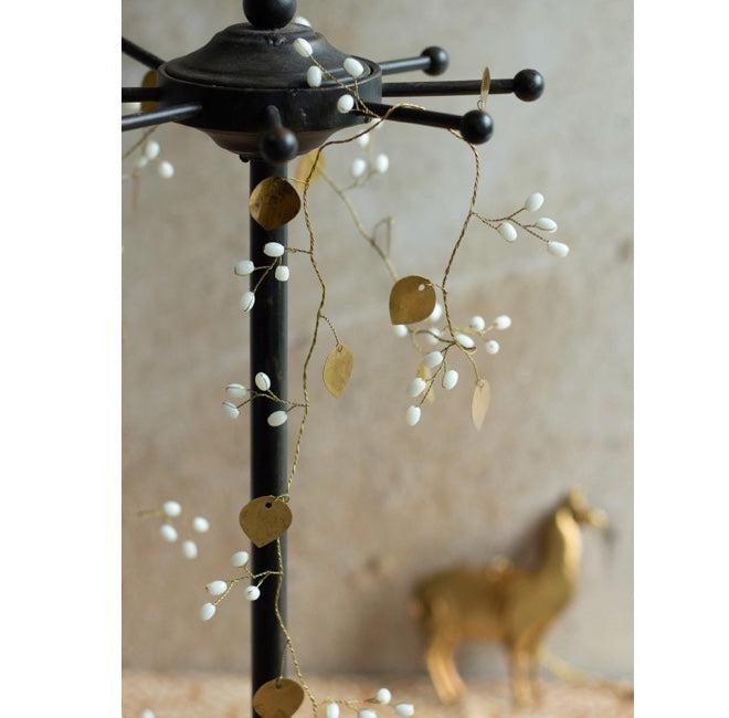 goldene deko girlande aus metall mit weißen beeren von der marke weldaad an einer garderobe dekoriert