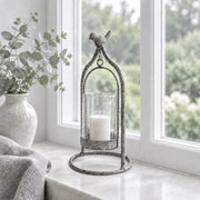 Windlicht aus grauem Metall mit einem Vogel als Deko der oben drauf sitzt und den Landhaus Stil shabby chic unterstreicht